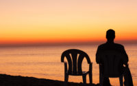 Man sits on chair alone in sunset