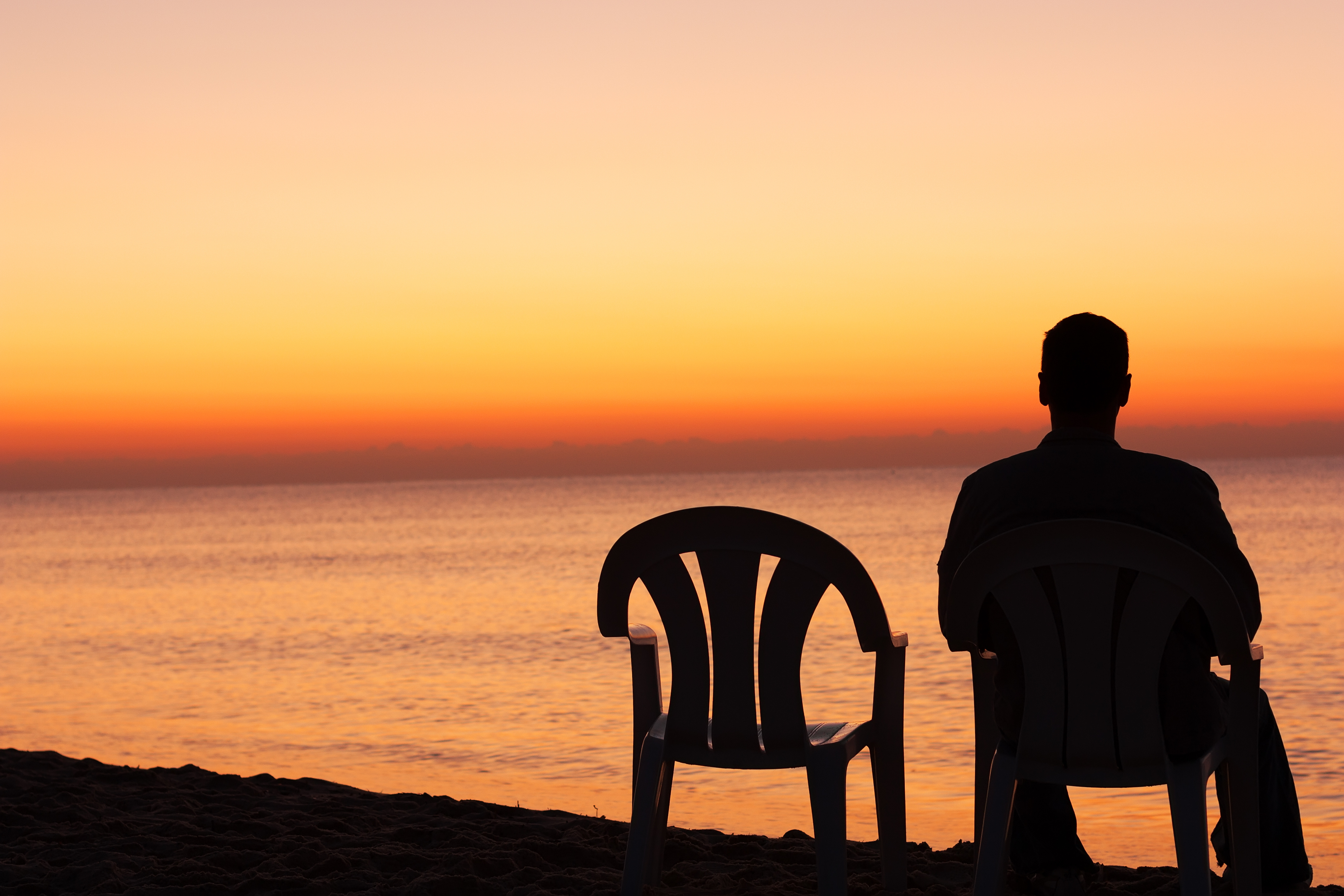 Man sits on chair alone in sunset